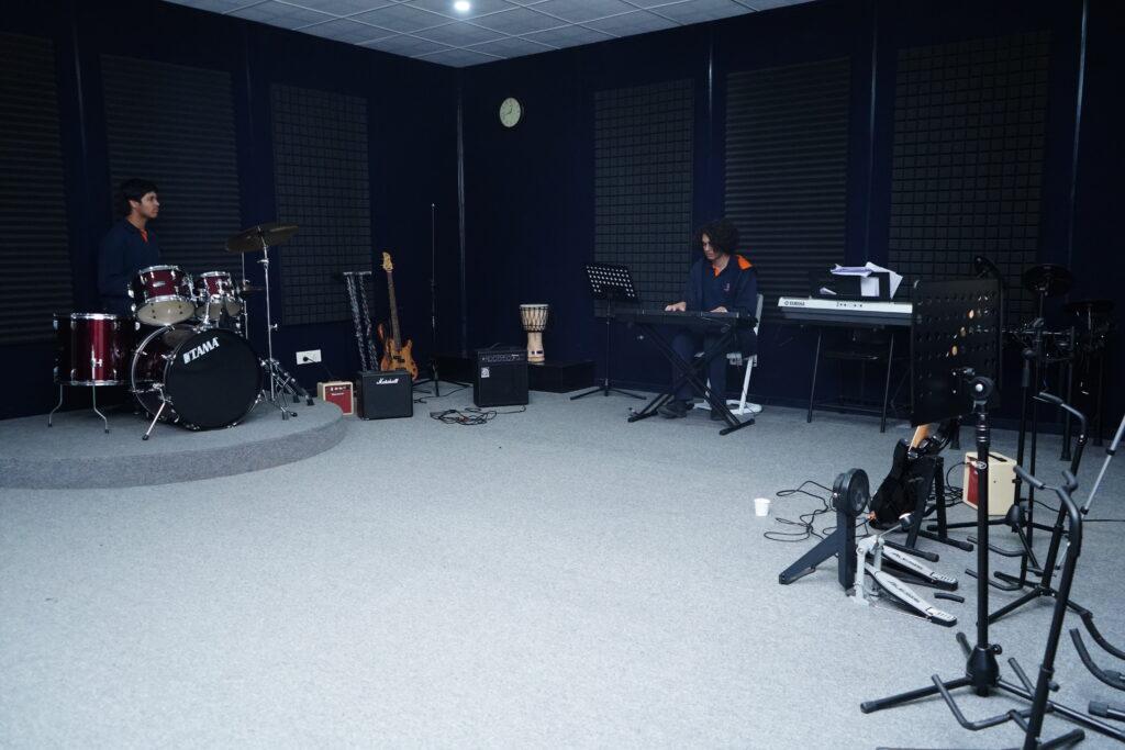 Secondary students playing drums and keyboard in the recording studio at Prometheus School