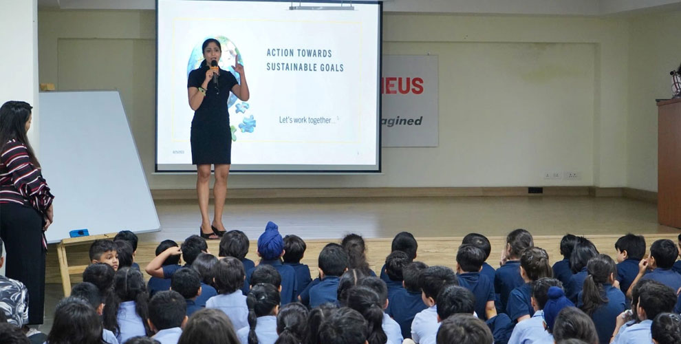 A presenter at Prometheus School is addressing a large group of students