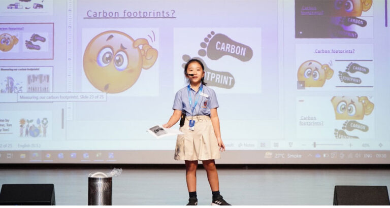 A girl is giving a presentation on carbon footprints, educating her peers on the importance of reducing individual and collective environmental impact at Prometheus School