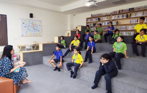 A teacher leading an engaging book reading session in the Primary Library at Prometheus School, captivating the young listeners