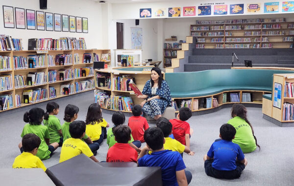 A teacher narrating a story during a reading session in the Primary Library, while students listen intently and enjoy the tale