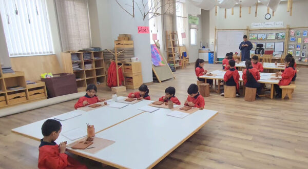 A vibrant art classroom where a group of Prometheus School students is actively engaged in creative activities, surrounded by art supplies and colourful artworks