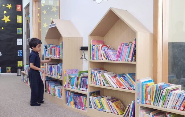 A young Prometheus School student browsing through the Early Years Library, searching for a book to enjoy