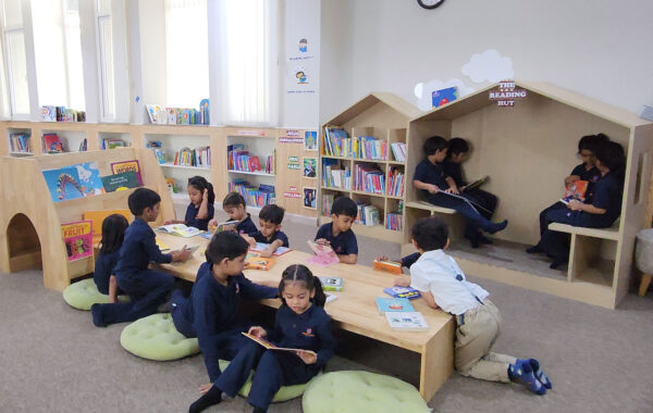 Early years students sitting together in the library, reading colourful books and enjoying the cozy space designed for young readers