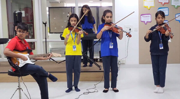 Prometheus School students practicing and playing the violin and guitar together in a collaborative music class
