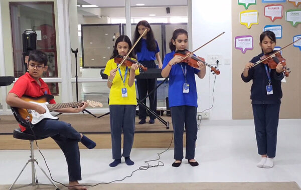 Prometheus School students practicing and playing the violin and guitar together in a collaborative music class
