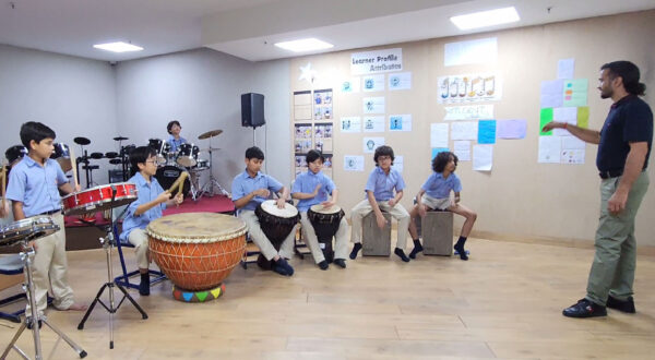 Prometheus School students practicing percussion instruments in class while their teacher provides guidance