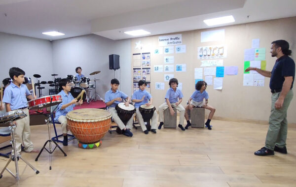 Prometheus School students practicing percussion instruments in class while their teacher provides guidance