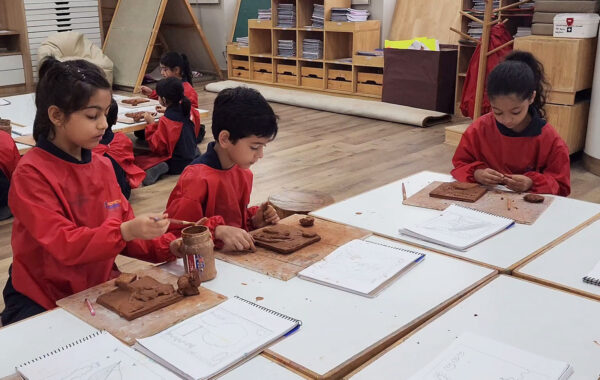 Prometheus School students shaping clay with focused expressions during a hands-on art session, with sculpting tools and clay pieces visible on the table