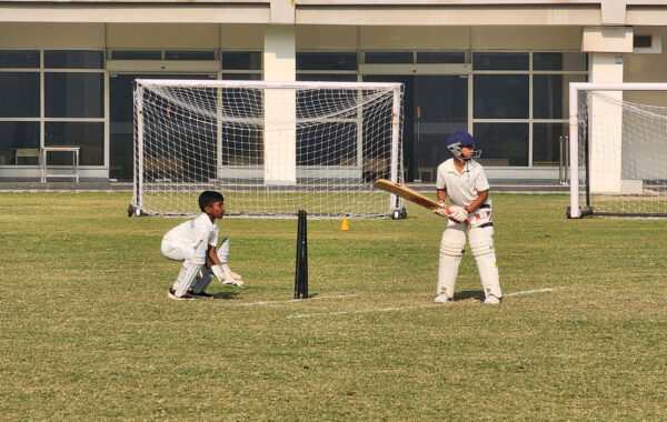Batsman on stance-Prometheus school batsman stands poised on strike while the wicketkeeper takes position behind the stumps