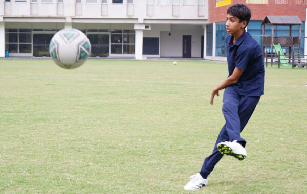 Focused kick-A Prometheus School student prepares and kicks the ball with precision during football practice
