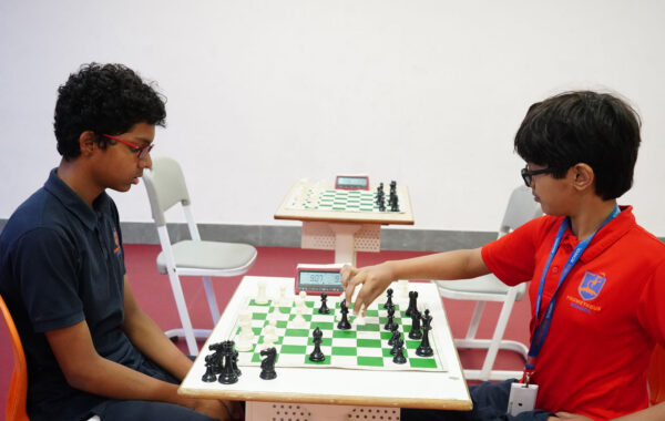 Prometheus Ruby house student moves a chess piece as their opponent remains in deep thought, planning a counter strategy