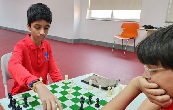 Ruby house students thoughtfully move chess pieces during an engaging match, showcasing strategic gameplay