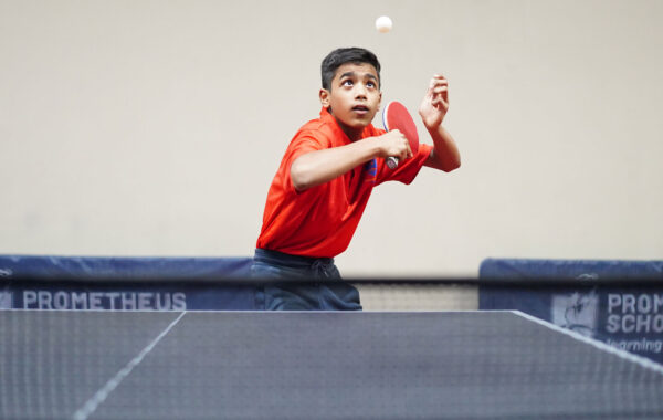 Skilled serve-A Prometheus School student swings the ball in the air, executing a focused service