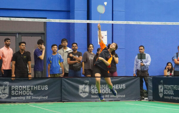 Smashing-A Prometheus School student strikes a powerful smash, aiming the shuttlecock with precision during an intense game