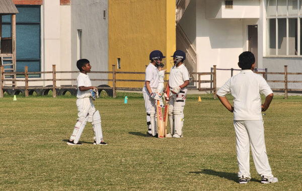 Strategic over break-During an over break, both Prometheus school batsmen discuss strategy while fielders adjust their positions on the field