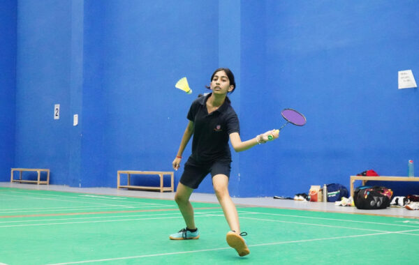 Swinging racquet-A Prometheus School student swings their racquet with energy while playing badminton, showcasing technique and skill